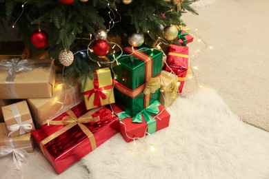 Photo of Decorated Christmas tree, beautiful gift boxes and festive lights on carpet