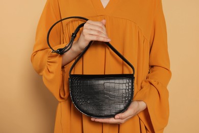 Woman with stylish bag on beige background, closeup