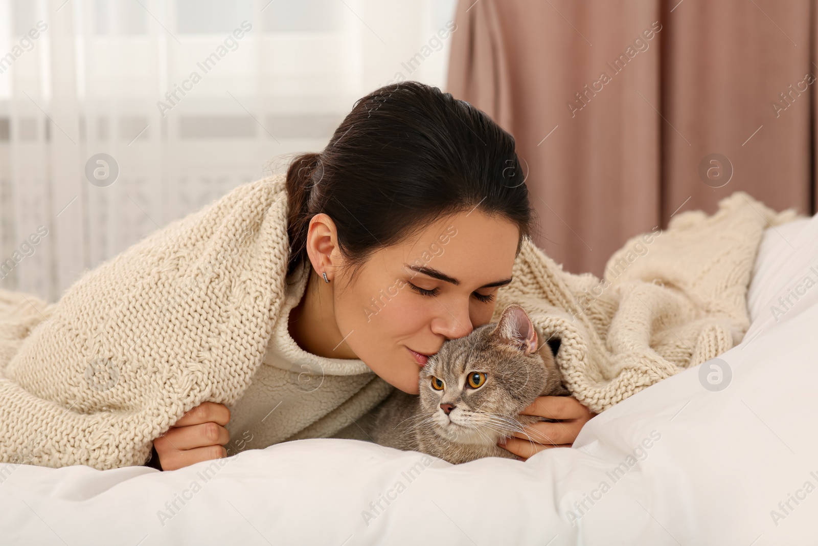 Photo of Young woman kissing her adorable cat at home