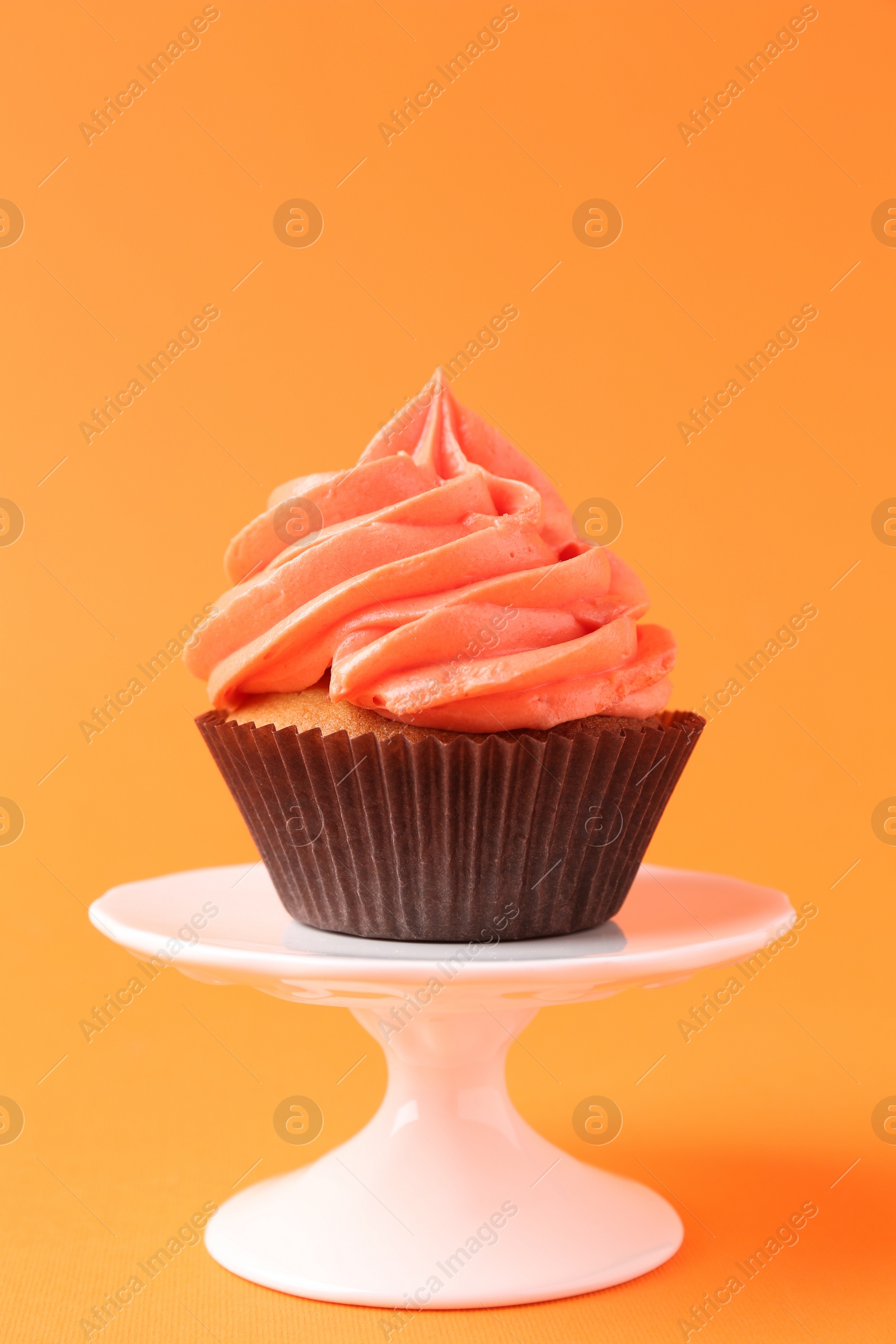 Photo of Delicious cupcake with bright cream on orange background