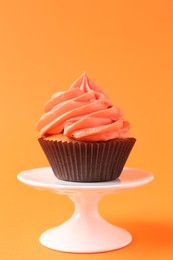 Photo of Delicious cupcake with bright cream on orange background