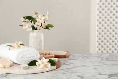 Photo of Composition with beautiful jasmine flowers and folded towel on white marble table, space for text