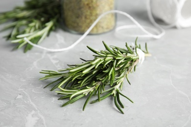 Jar with dried rosemary, twine and fresh twigs on grey table