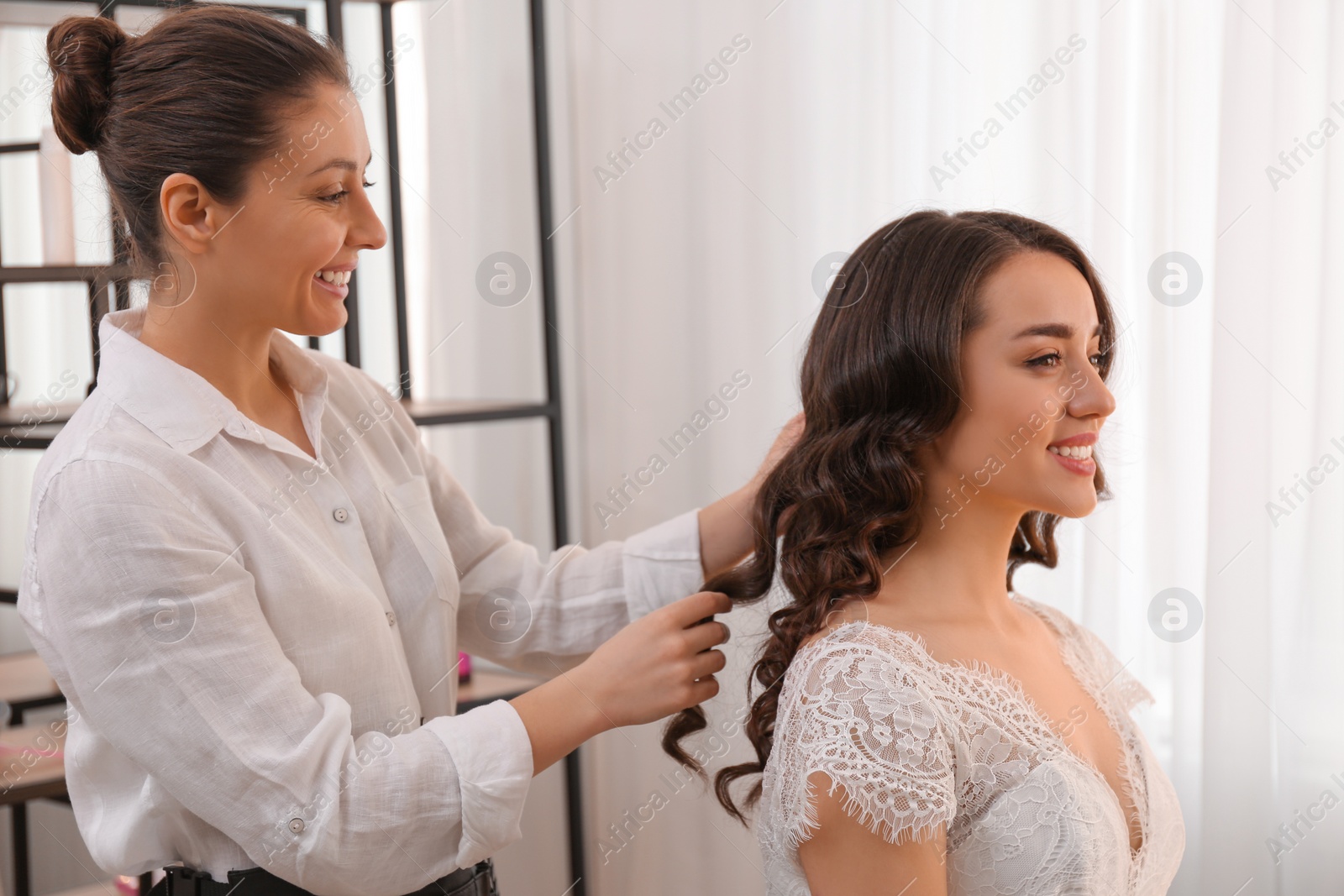 Photo of Stylist working with client in salon, making wedding hairstyle