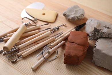 Clay and set of modeling tools on wooden table, closeup