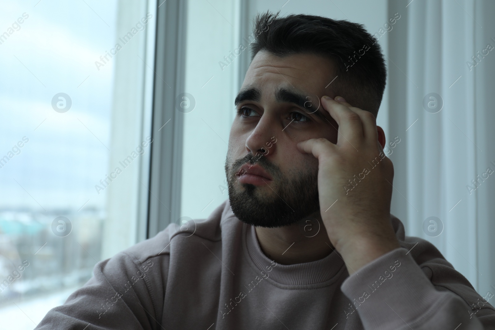 Photo of Portrait of sad man near window at home