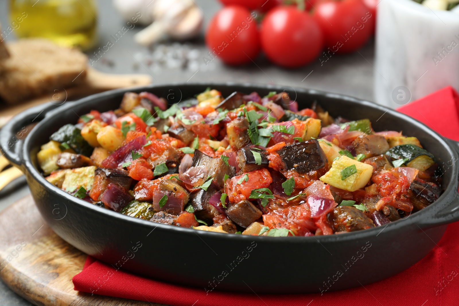 Photo of Dish with tasty ratatouille on wooden board, closeup