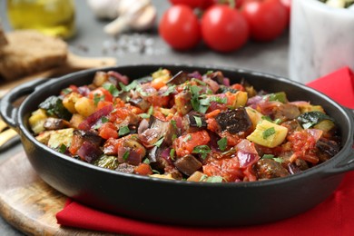 Photo of Dish with tasty ratatouille on wooden board, closeup