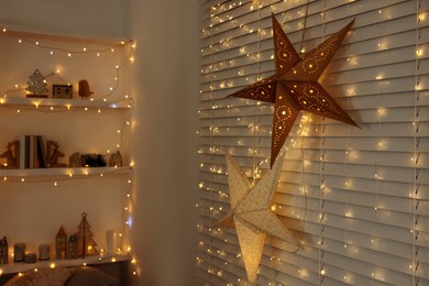Beautiful decorative stars and festive lights in room. Christmas atmosphere