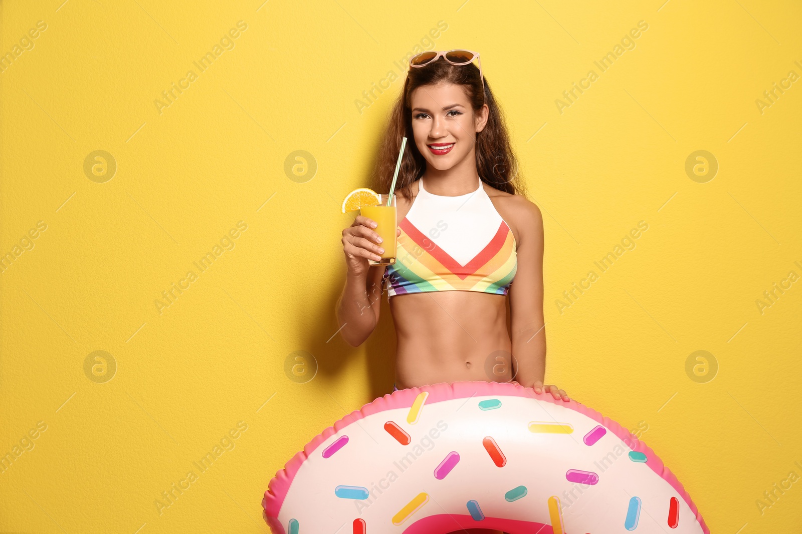 Photo of Beautiful young woman with inflatable ring and glass of cocktail on color background