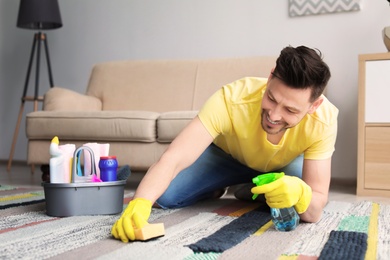 Mature man cleaning carpet at home