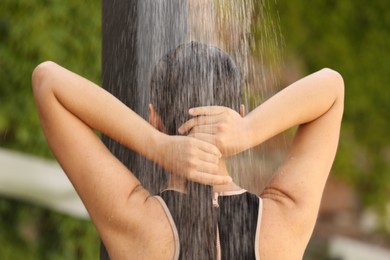 Woman washing hair in outdoor shower on summer day