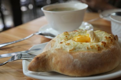 Fresh delicious Adjarian khachapuri with cheese and egg on wooden table, closeup