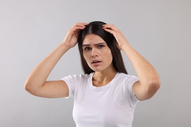 Photo of Emotional woman examining her hair and scalp on grey background