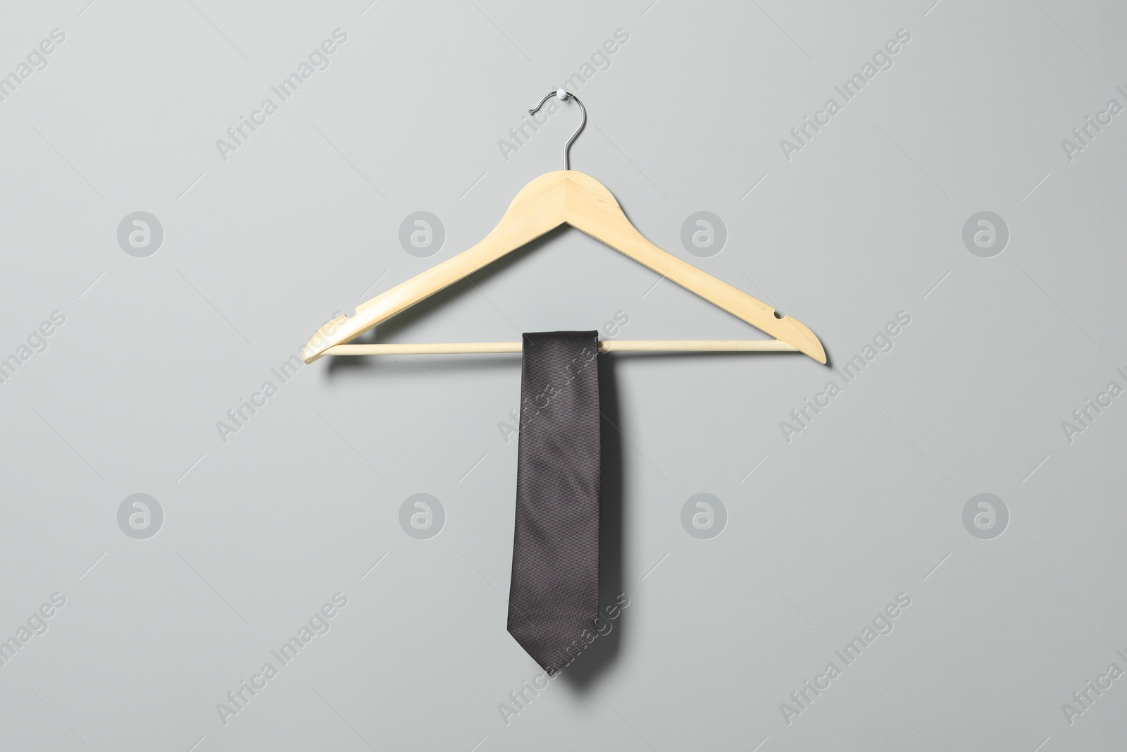 Photo of Hanger with necktie on light grey wall