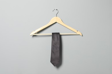 Photo of Hanger with necktie on light grey wall
