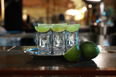 Photo of Mexican Tequila shots with lime slices on bar counter