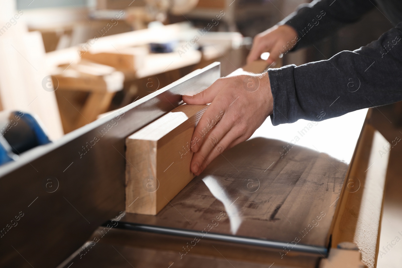 Photo of Professional carpenter working with surface planer in workshop, closeup