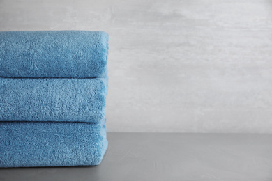 Photo of Stack of clean bath towels on grey table. Space for text