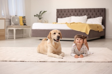 Photo of Adorable yellow labrador retriever and little girl at home