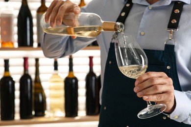 Photo of Bartender pouring wine into glass in restaurant, closeup