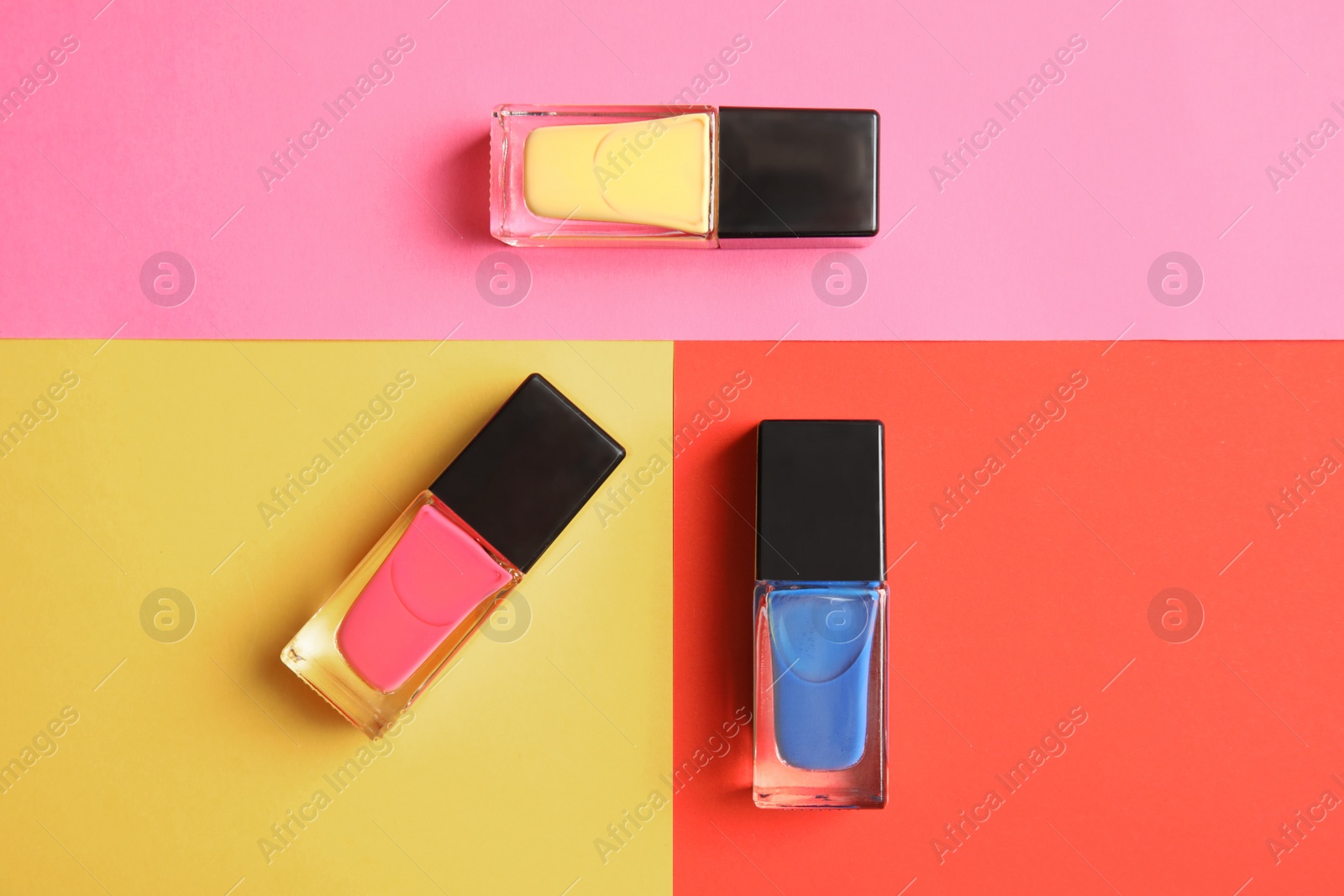 Photo of Bottles of nail polish on color background, top view