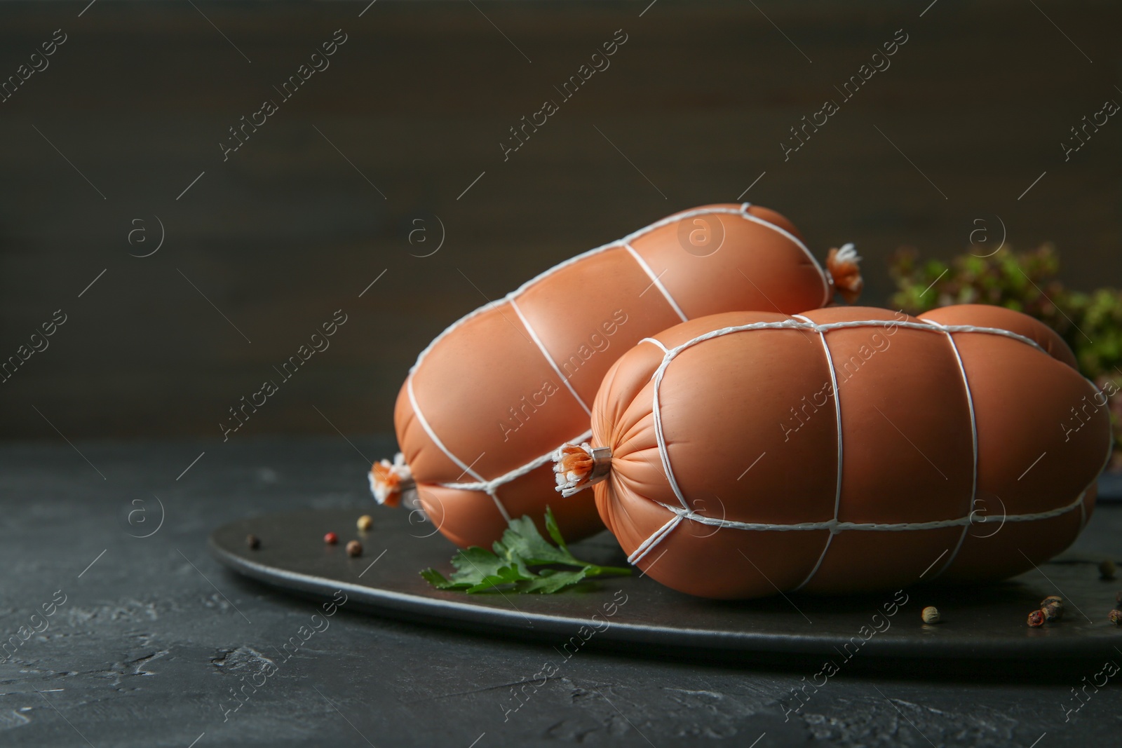 Photo of Tasty boiled sausages on dark textured table, closeup. Space for text