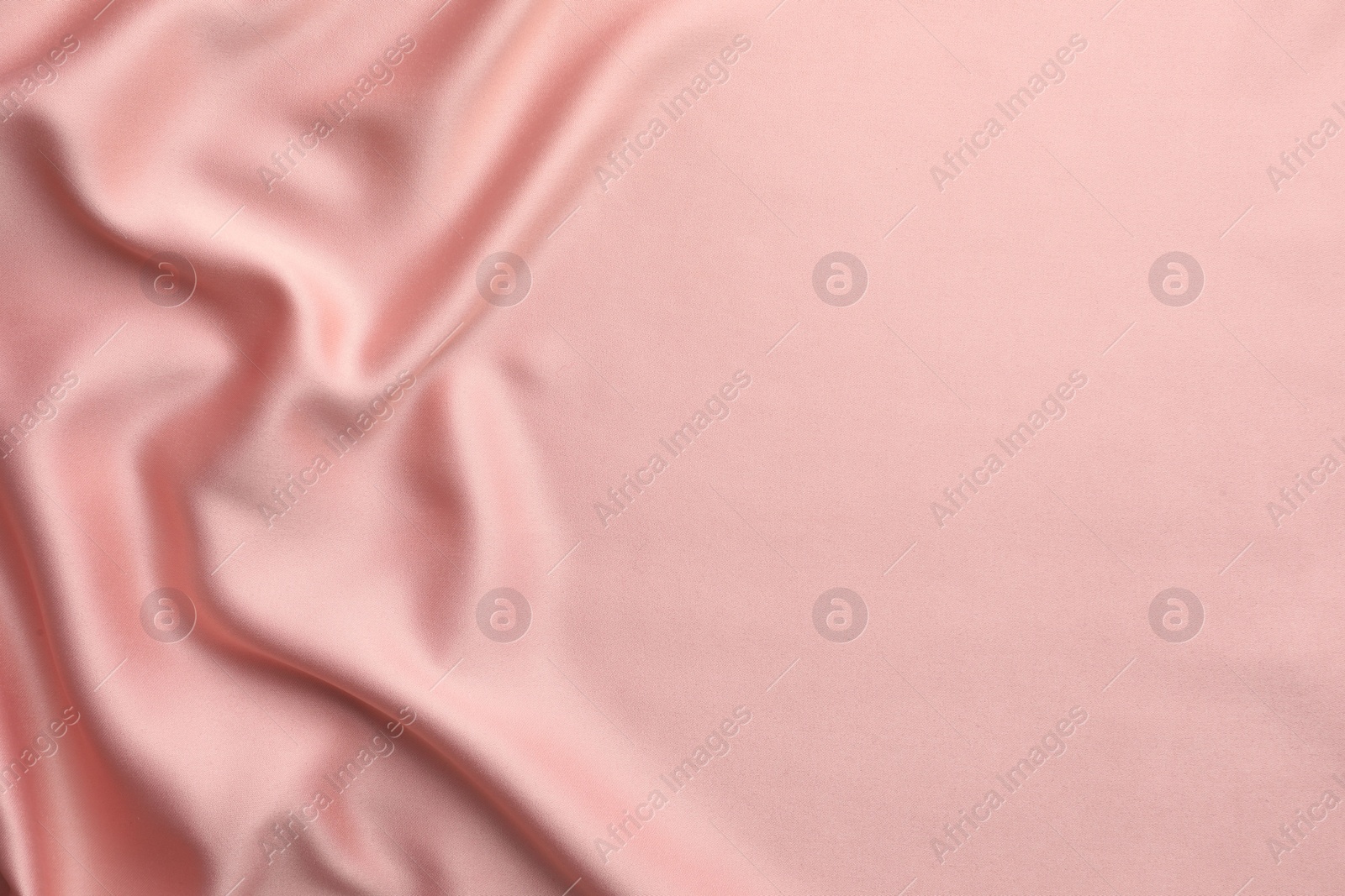 Photo of Crumpled pink silk fabric as background, top view. Space for text