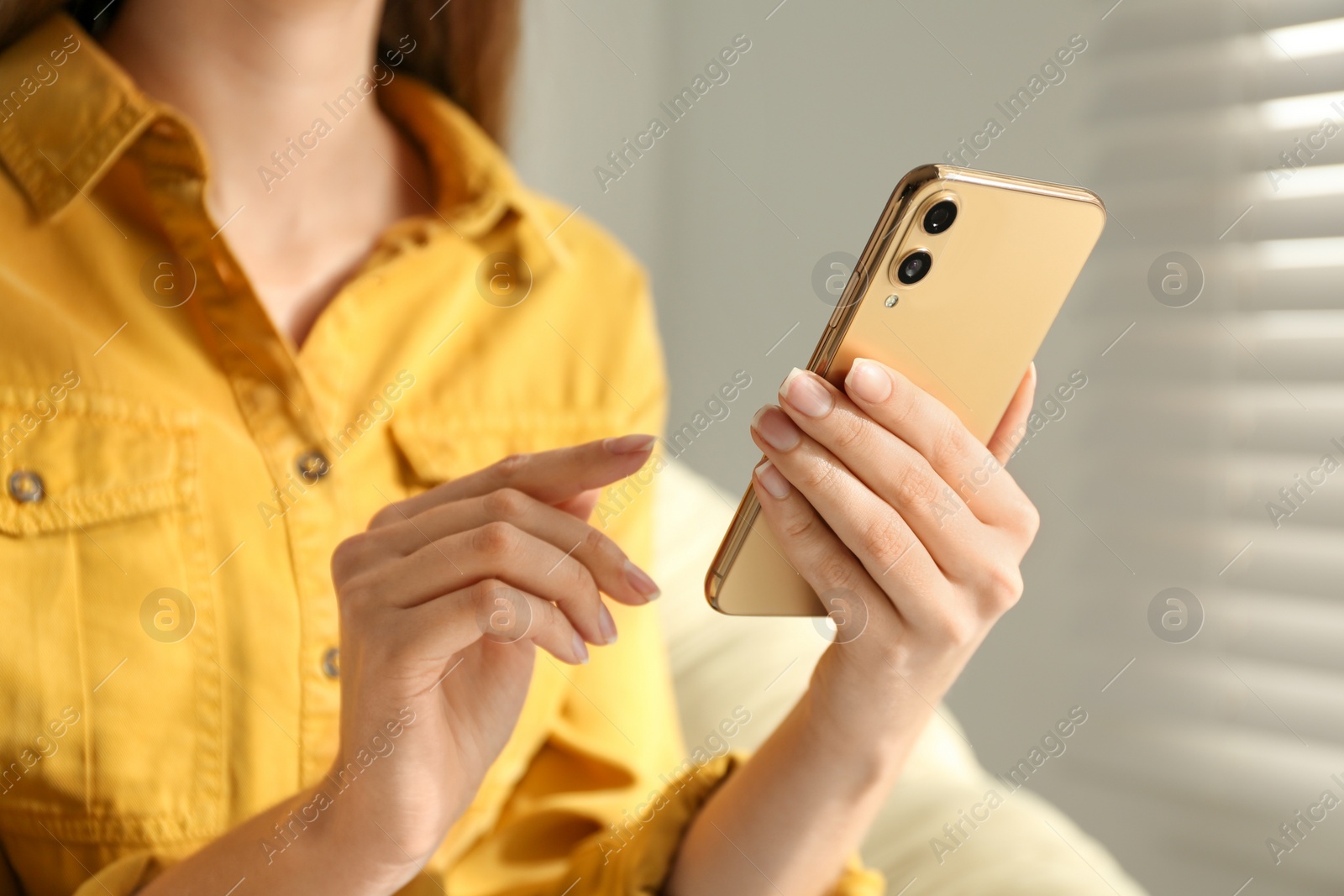 Photo of Young woman using modern smartphone indoors, closeup