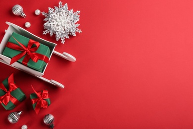 Photo of Beautiful Christmas composition with miniature sleigh on red background, flat lay. Space for text