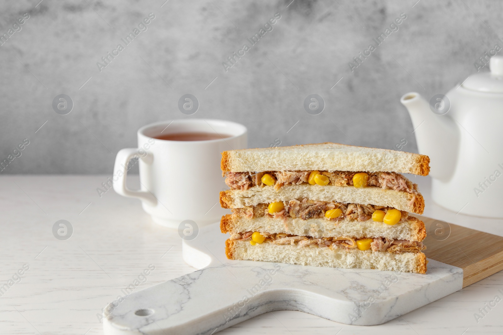 Photo of Delicious sandwich with tuna and corn on white wooden table, space for text