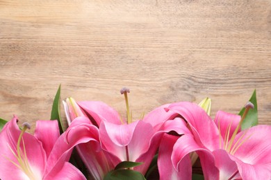 Photo of Beautiful pink lily flowers on wooden table, top view. Space for text