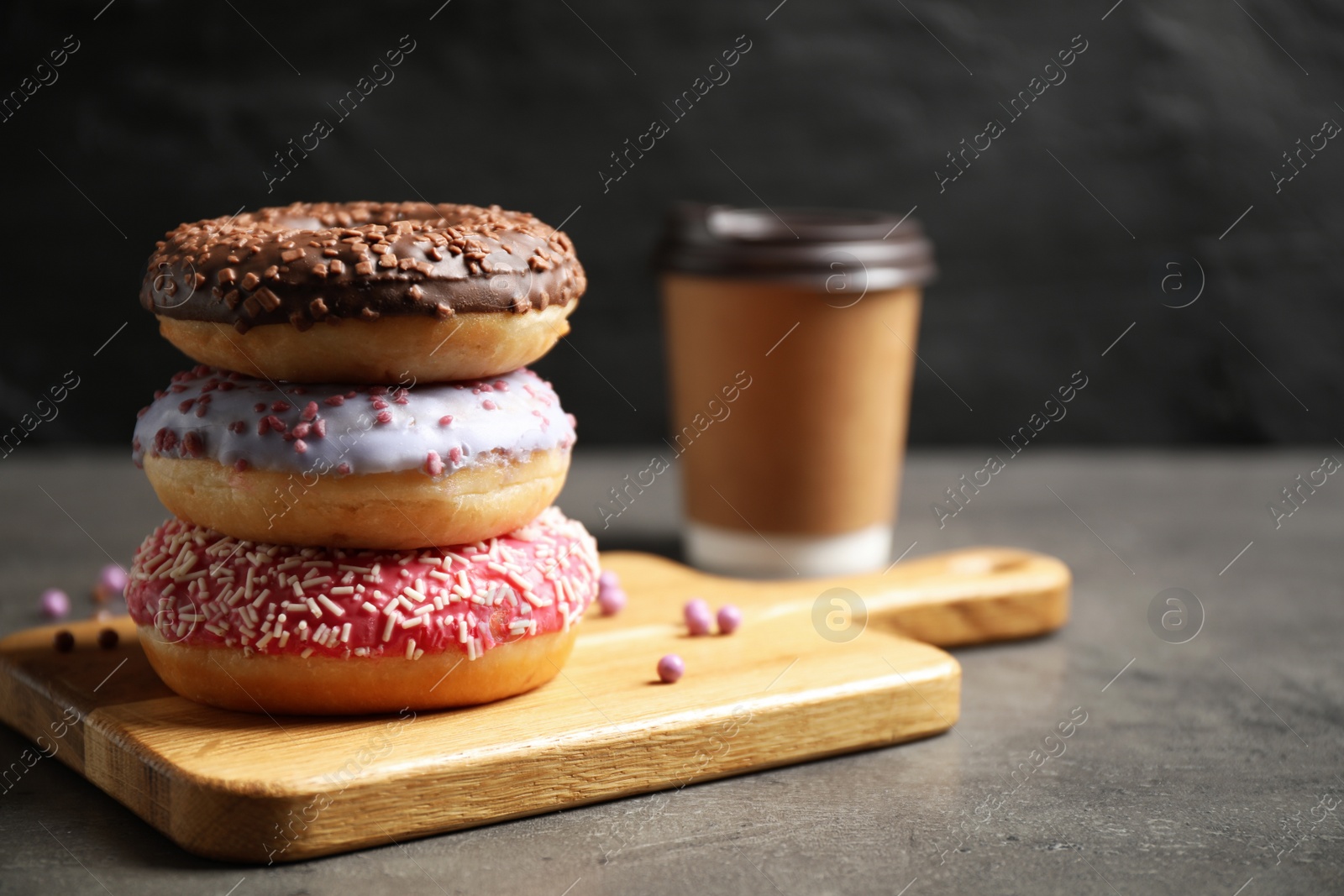 Photo of Sweet delicious glazed donuts on grey table, space for text