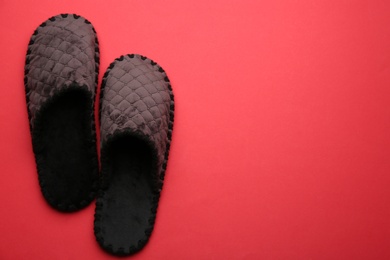 Pair of soft slippers on red background, flat lay. Space for text