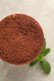 Photo of Delicious tiramisu in glass and mint on grey table, top view