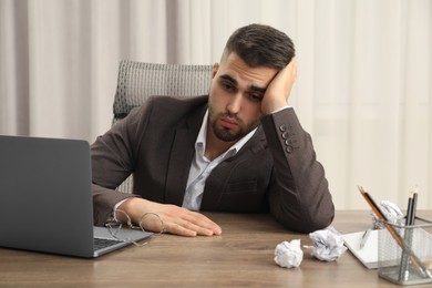 Photo of Tired sad businessman sitting at table in office