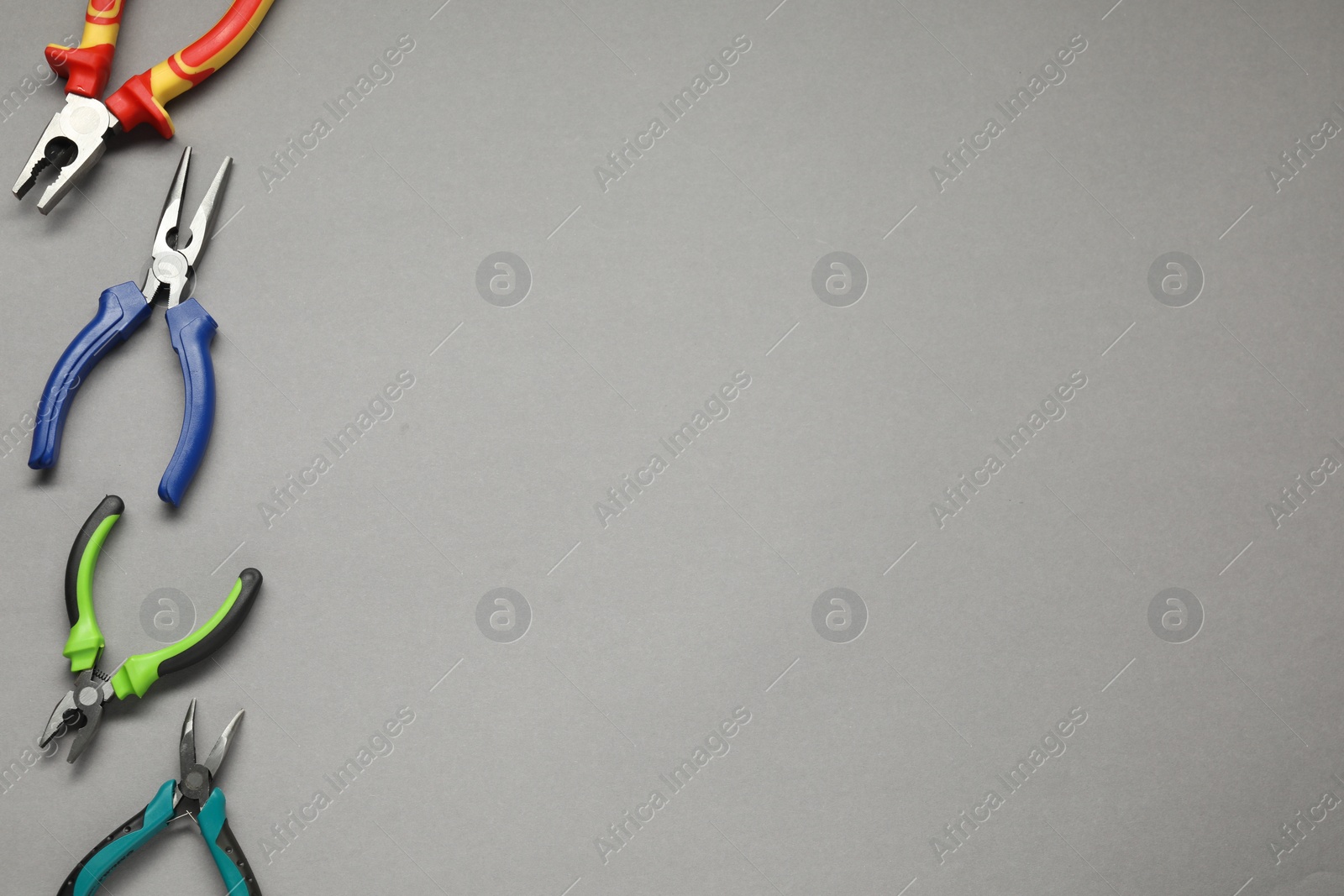 Photo of Different pliers on grey background, flat lay. Space for text