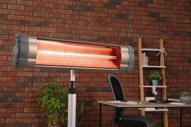 Photo of Electric infrared heater near brick wall in stylish room