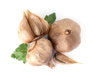 Aged black garlic with parsley on white background, view from above