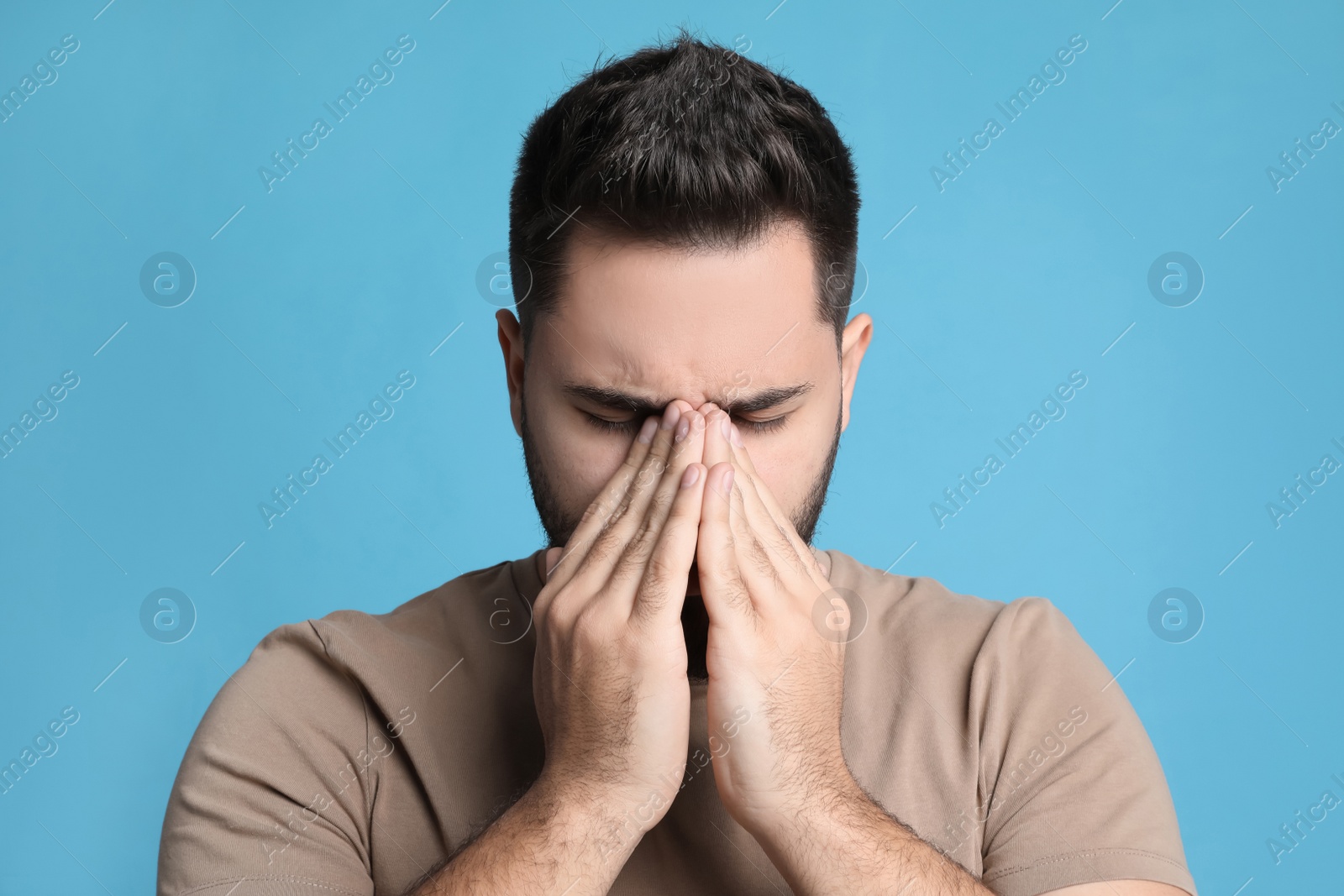 Photo of Young man suffering from headache on light blue background