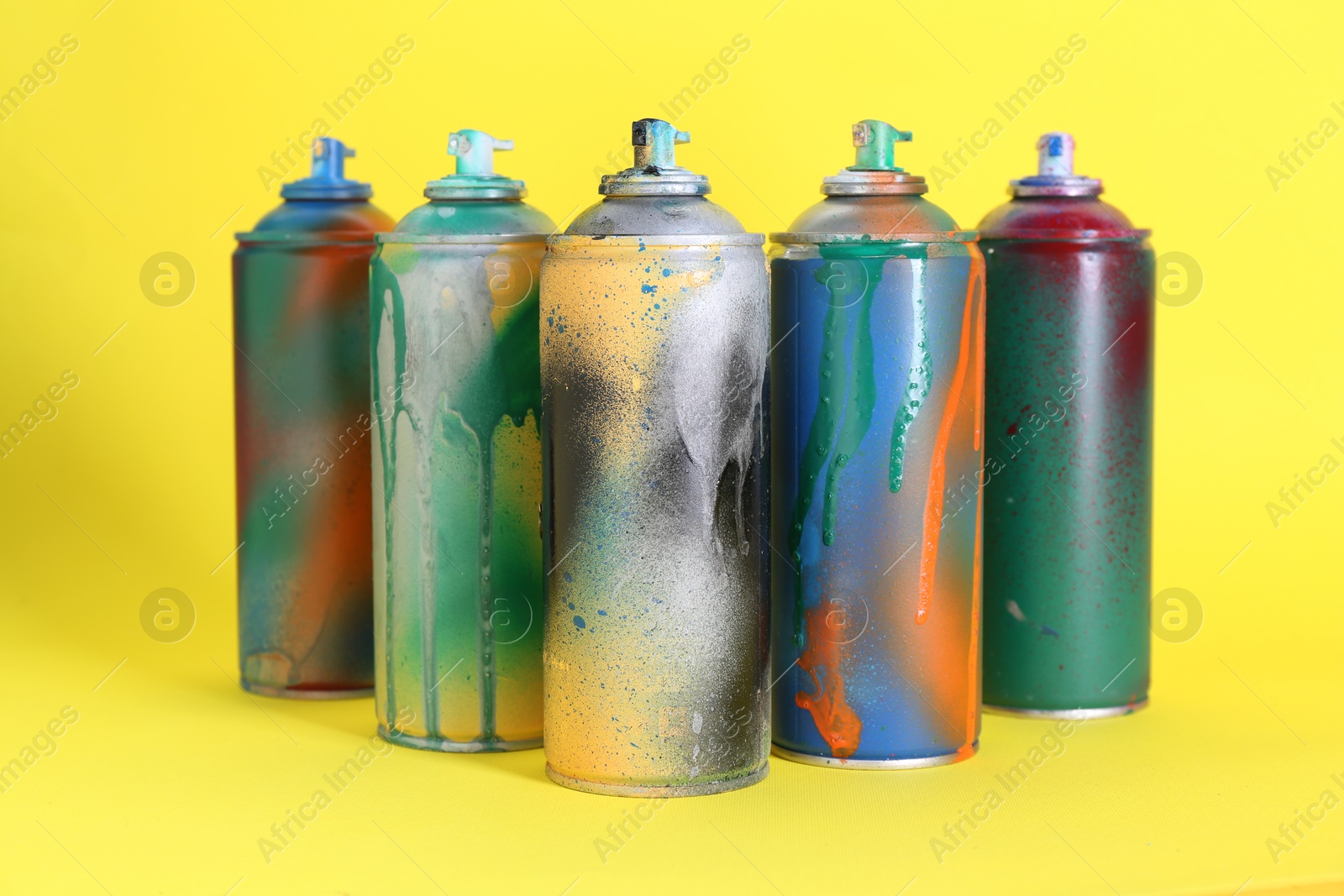 Photo of Many spray paint cans on yellow background