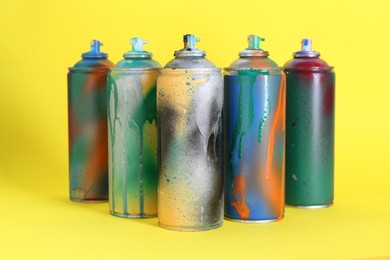 Photo of Many spray paint cans on yellow background