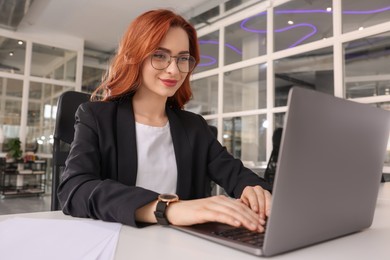 Photo of Woman working with laptop at white desk in office