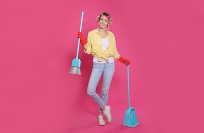 Photo of Young housewife with broom and dustpan on pink background