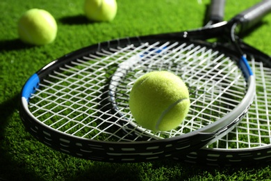 Photo of Tennis rackets and balls on green grass, closeup. Sports equipment