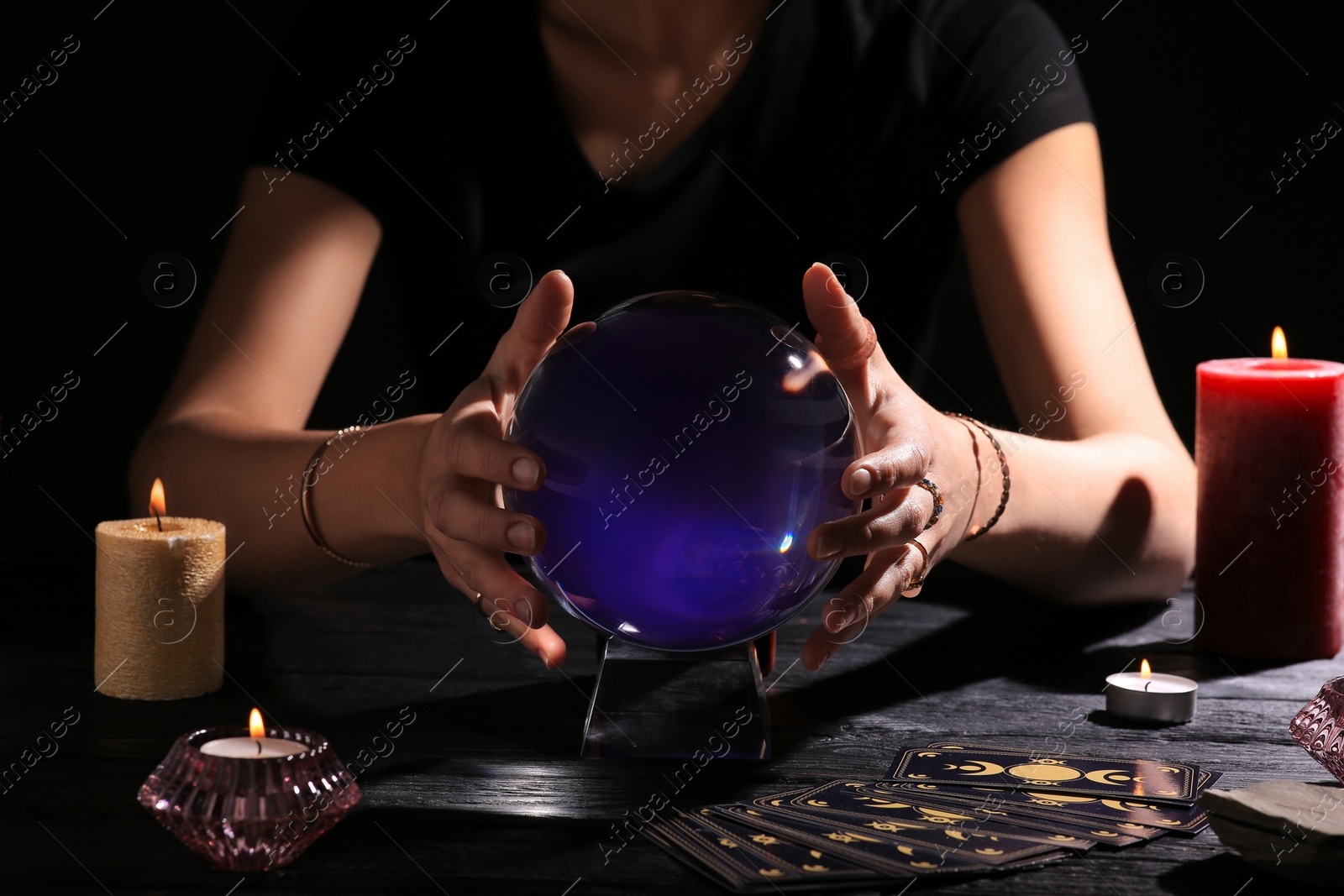 Photo of Soothsayer using crystal ball to predict future at table in darkness, closeup