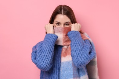 Beautiful woman in warm scarf on pink background