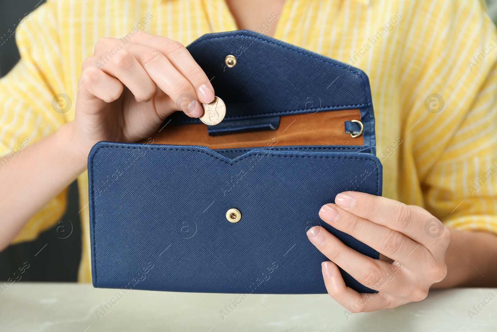 Photo of Woman putting coin into wallet at light table, closeup