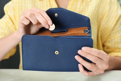 Photo of Woman putting coin into wallet at light table, closeup