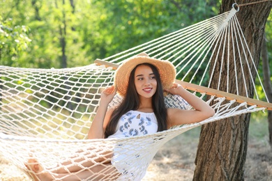 Photo of Young woman resting in comfortable hammock at green garden